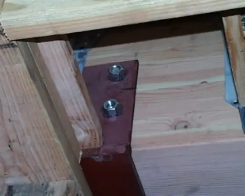 Close-up of a structural beam connection with bolts and wood framing, highlighting issues in construction inspections.